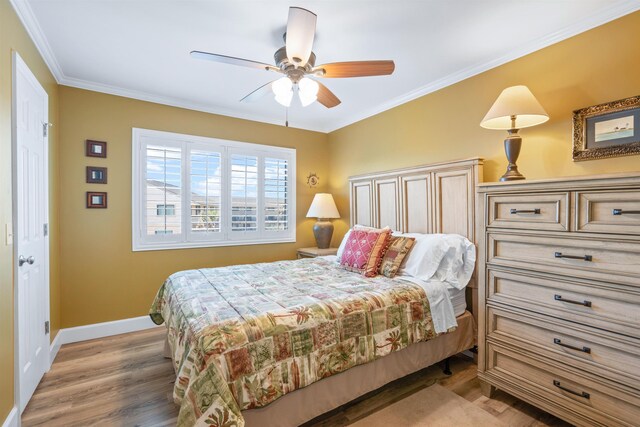 bedroom with ceiling fan, crown molding, baseboards, and wood finished floors