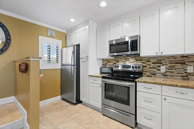 kitchen featuring appliances with stainless steel finishes, white cabinetry, crown molding, and light stone counters