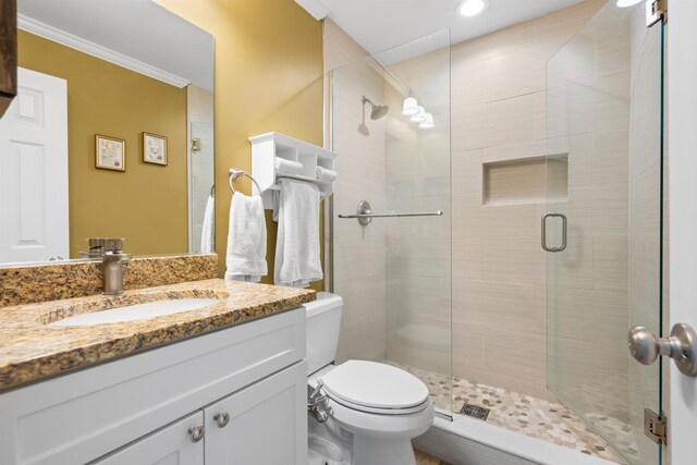 bathroom with toilet, crown molding, a shower stall, and vanity