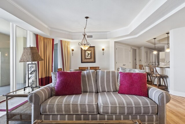 living room with wood-type flooring, crown molding, and a tray ceiling