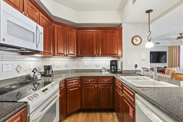 kitchen featuring sink, white appliances, hanging light fixtures, backsplash, and light wood-type flooring