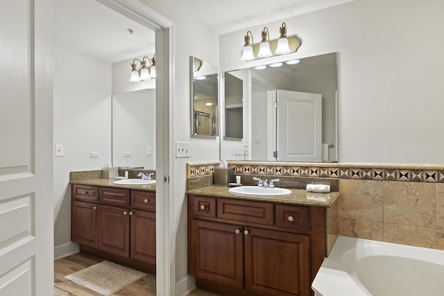 bathroom featuring vanity, hardwood / wood-style floors, and a tub to relax in