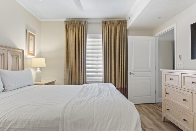 bedroom with ornamental molding, ceiling fan, and light hardwood / wood-style flooring