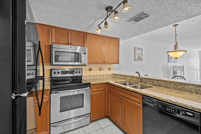 8200 S A1A Unit 15, Saint Augustine, FL 32080 - kitchen featuring black appliances, a textured ceiling, light stone countertops, brown cabinetry, and pendant lighting
