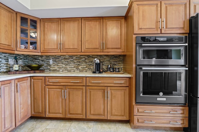 821 Kalli Creek Ln, Saint Augustine, FL 32080 - kitchen with double wall oven, brown cabinetry, decorative backsplash, and glass insert cabinets