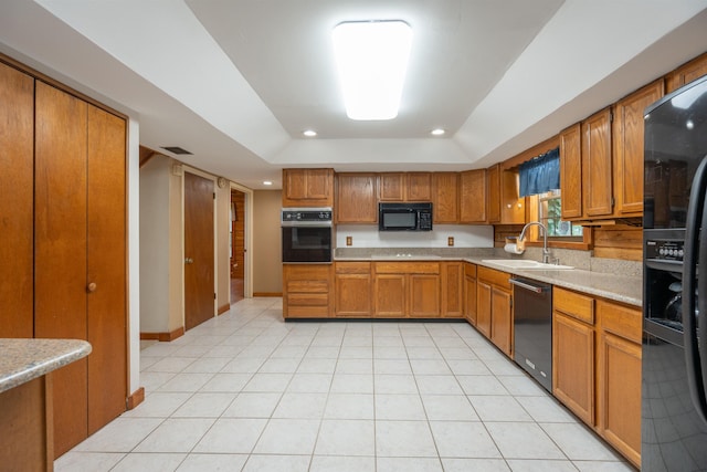 kitchen with black appliances, sink, light stone countertops, light tile patterned floors, and a tray ceiling