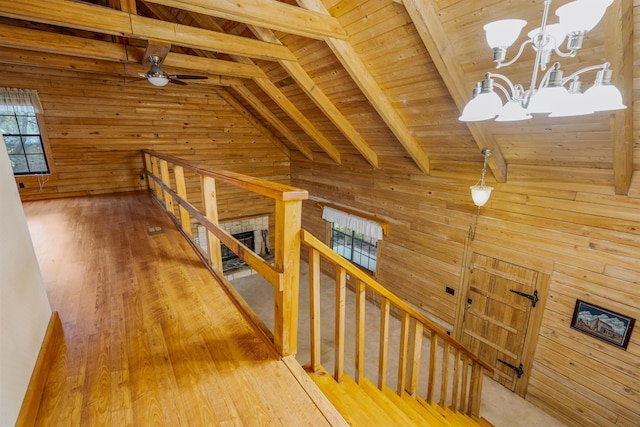 hall with hardwood / wood-style floors, vaulted ceiling with beams, wood walls, and a notable chandelier