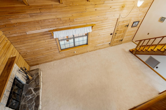 unfurnished living room featuring high vaulted ceiling, wooden ceiling, a fireplace, and wooden walls