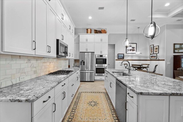 587 Pescado Dr, Saint Augustine, FL 32095 - kitchen featuring stainless steel appliances, crown molding, white cabinetry, decorative backsplash, and an island with sink