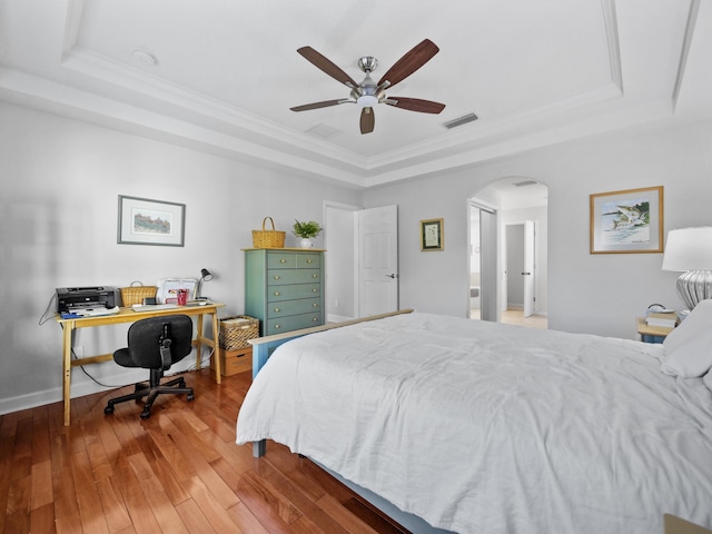 bedroom featuring a raised ceiling, ornamental molding, and hardwood / wood-style floors