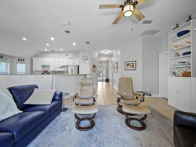 tiled living room featuring ceiling fan, vaulted ceiling, and a textured ceiling