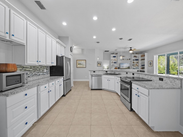 kitchen with appliances with stainless steel finishes, sink, white cabinets, and kitchen peninsula