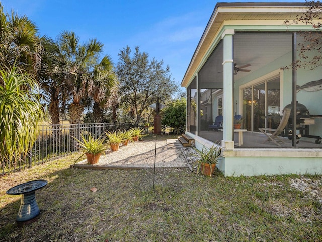 view of yard featuring ceiling fan and a sunroom