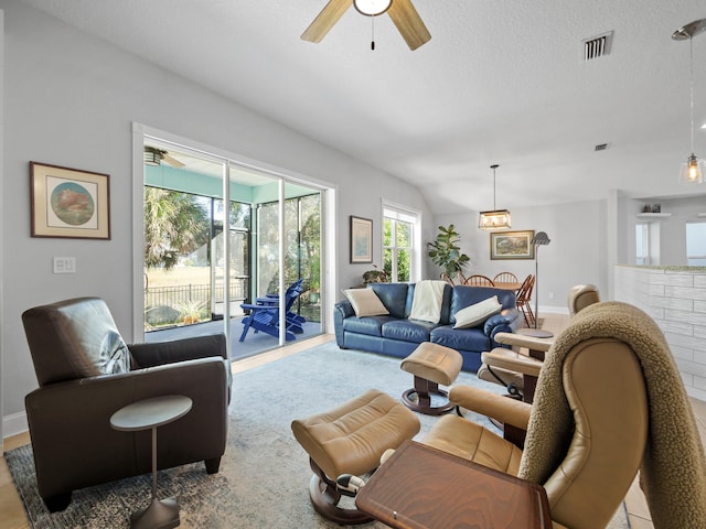 living room featuring vaulted ceiling, a textured ceiling, and ceiling fan