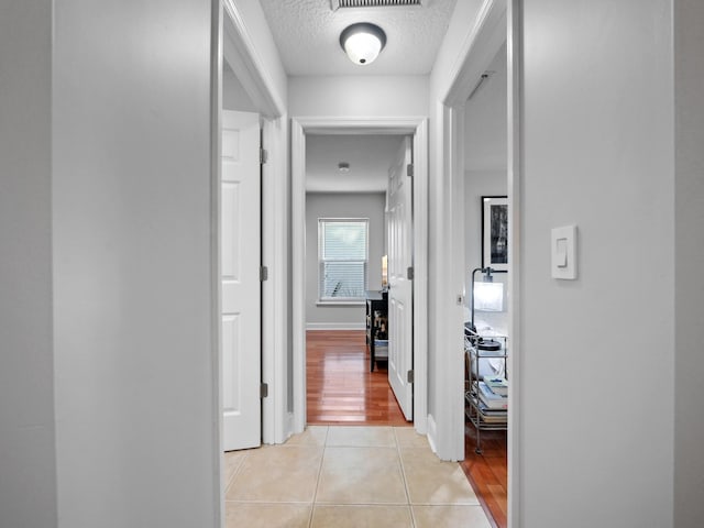 corridor with light tile patterned floors and a textured ceiling