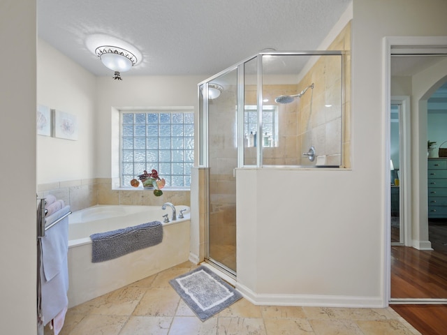 bathroom with shower with separate bathtub and a textured ceiling