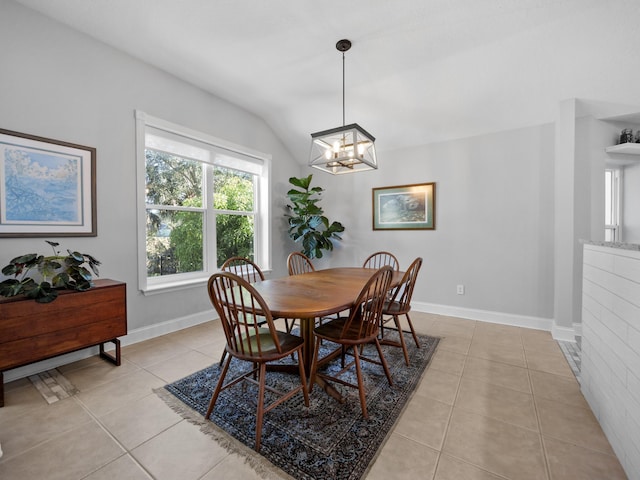 tiled dining space with lofted ceiling and a chandelier