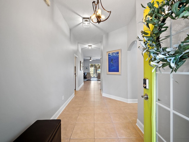 hall with an inviting chandelier, light tile patterned floors, and a textured ceiling