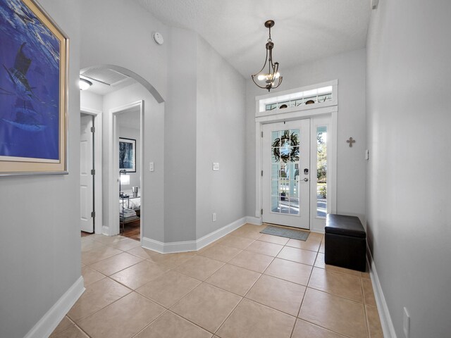 tiled foyer featuring an inviting chandelier and a textured ceiling