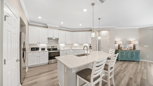 kitchen featuring light wood-type flooring, stainless steel appliances, sink, pendant lighting, and white cabinetry