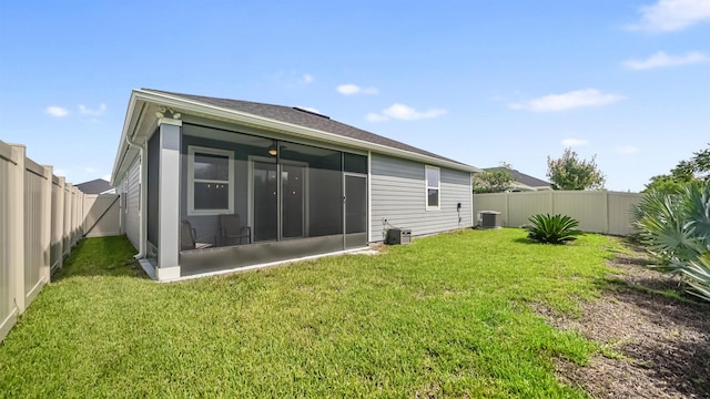 back of property with a sunroom, central air condition unit, and a lawn