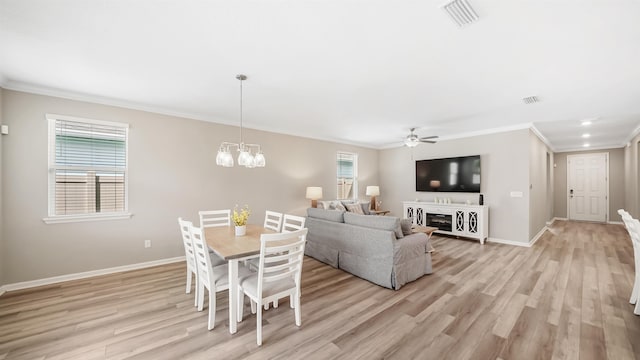 living room with ceiling fan with notable chandelier, light wood-type flooring, and ornamental molding