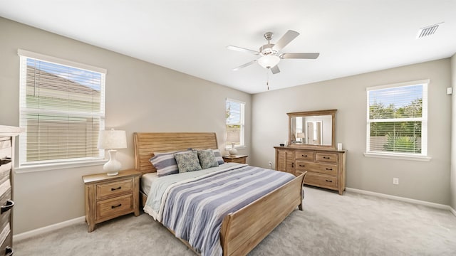 bedroom with light carpet, multiple windows, and ceiling fan