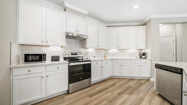 kitchen featuring white cabinetry, light hardwood / wood-style flooring, backsplash, appliances with stainless steel finishes, and ornamental molding