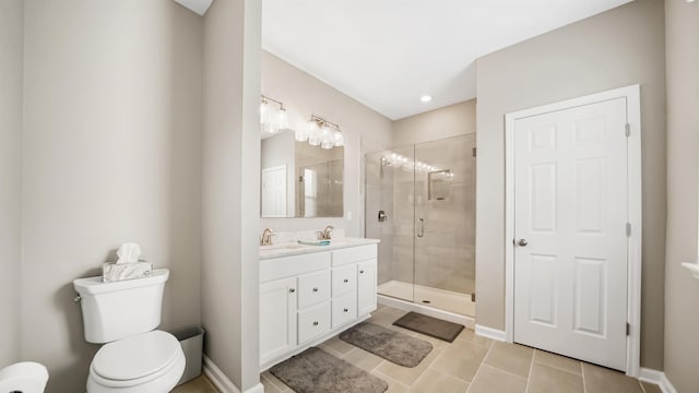 bathroom featuring tile patterned floors, vanity, a shower with shower door, and toilet