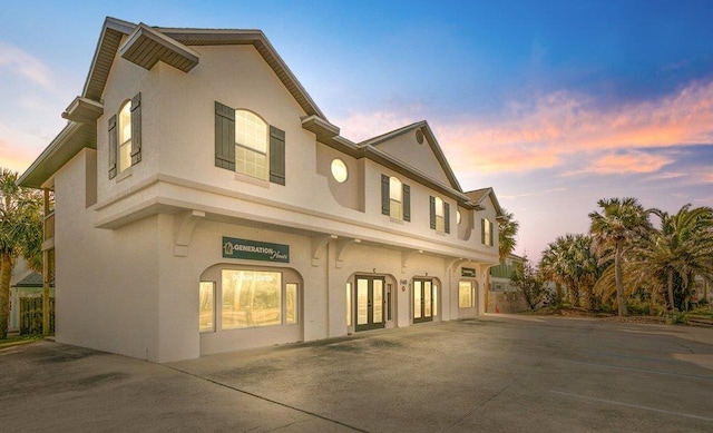 view of front facade with stucco siding and french doors