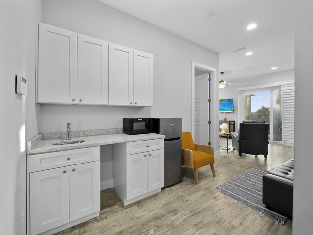 5813 Rudolph Ave, Saint Augustine, FL 32080 - kitchen with white cabinetry, a sink, light wood-style floors, and black microwave