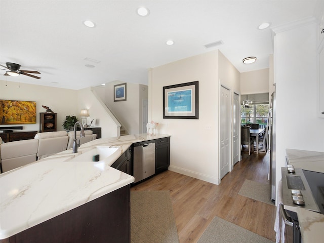 kitchen with sink, light hardwood / wood-style flooring, appliances with stainless steel finishes, light stone counters, and kitchen peninsula