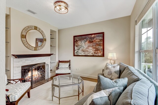 living room with a stone fireplace and built in shelves