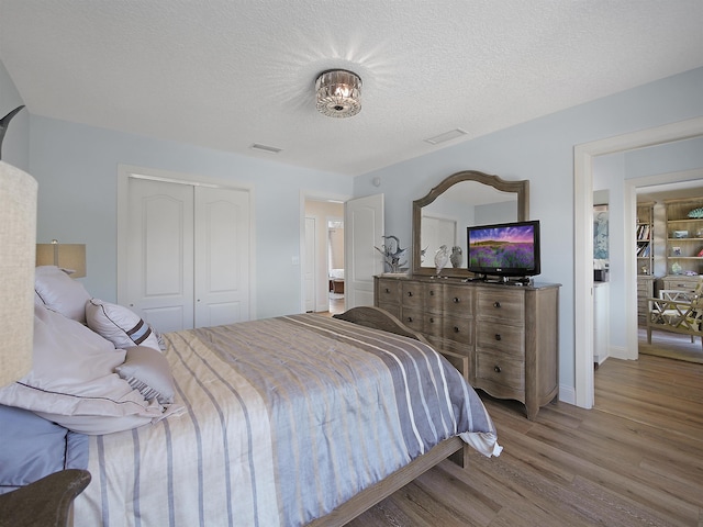 bedroom featuring a closet, a textured ceiling, and light wood-type flooring