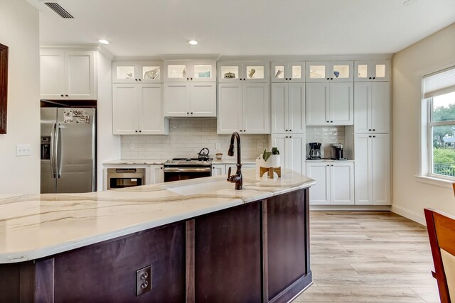 kitchen featuring sink, light hardwood / wood-style flooring, dishwasher, a water view, and light stone countertops