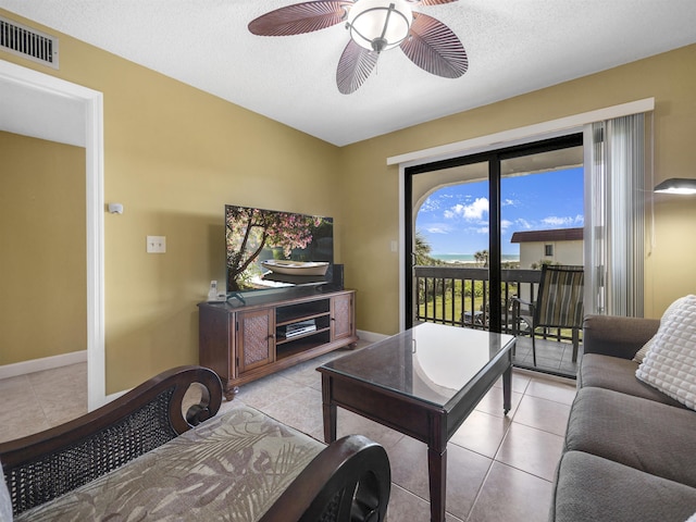 living room featuring ceiling fan, light tile patterned floors, and a textured ceiling