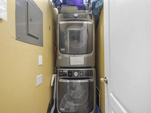 laundry area with electric panel and stacked washer and dryer