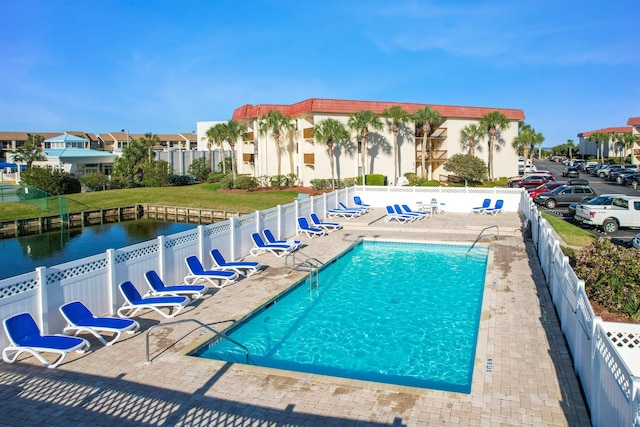 view of pool featuring a water view and a patio