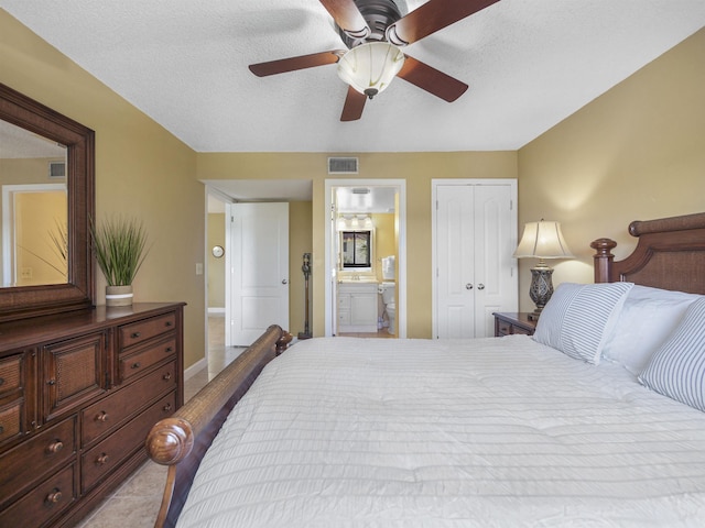 bedroom with ensuite bath, ceiling fan, a textured ceiling, a closet, and light tile patterned floors