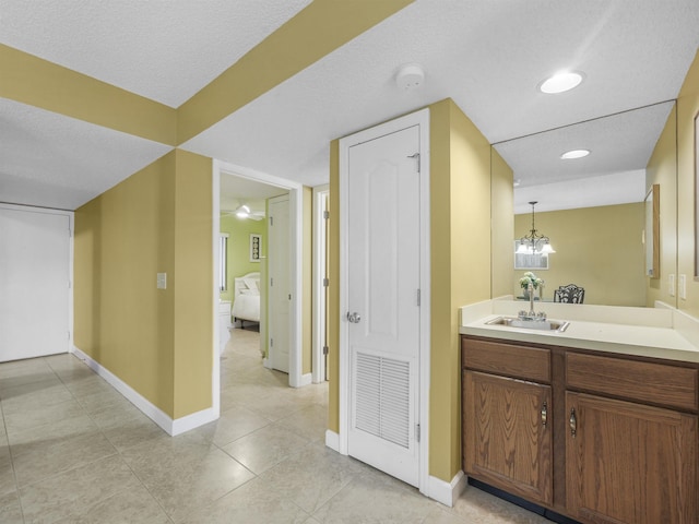 bathroom featuring tile patterned flooring, vanity, a chandelier, and a textured ceiling