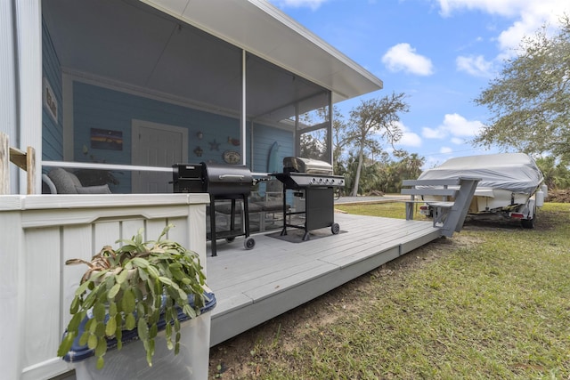 wooden terrace featuring a lawn, a sunroom, and a grill