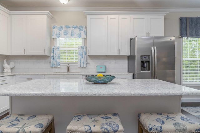 kitchen featuring stainless steel fridge, sink, white cabinets, and a healthy amount of sunlight