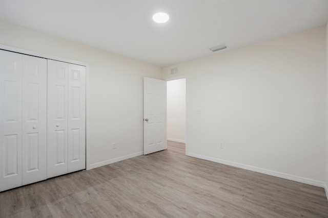 unfurnished bedroom with a closet and light hardwood / wood-style flooring