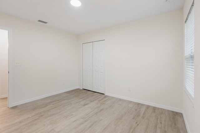 unfurnished bedroom with light wood-type flooring and a closet