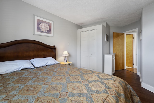 bedroom with a textured ceiling, a closet, and dark wood-type flooring