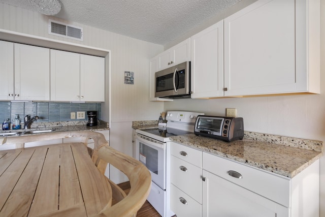 kitchen featuring sink, white electric range oven, light stone counters, a textured ceiling, and white cabinets