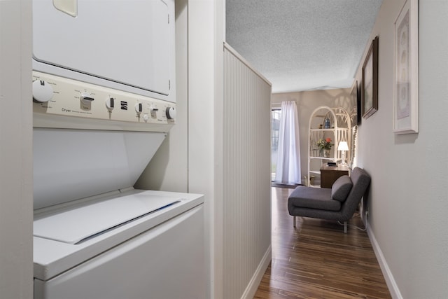 corridor with a textured ceiling, stacked washer / dryer, and dark wood-type flooring