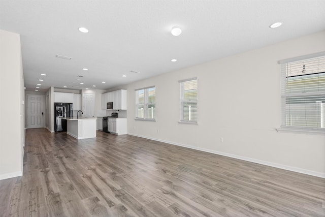 638 Honeycomb Trl, Saint Augustine, FL 32095 - unfurnished living room featuring baseboards, light wood-style flooring, recessed lighting, and a sink