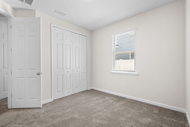 638 Honeycomb Trl, Saint Augustine, FL 32095 - unfurnished bedroom featuring baseboards, a textured ceiling, carpet floors, visible vents, and a closet