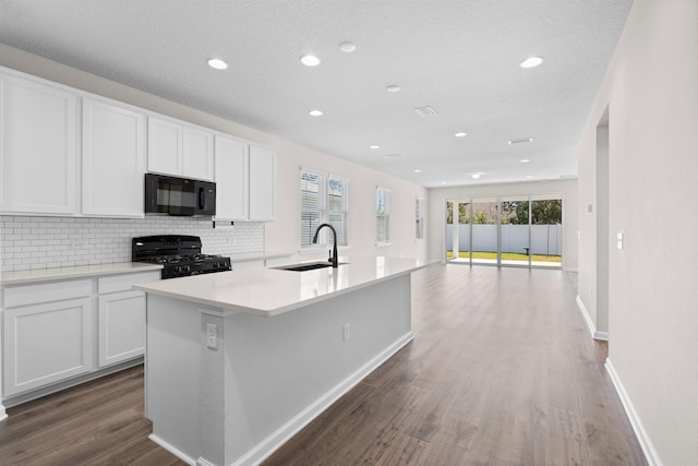 638 Honeycomb Trl, Saint Augustine, FL 32095 - kitchen with decorative backsplash, dark wood-style flooring, a kitchen island with sink, a sink, and black appliances